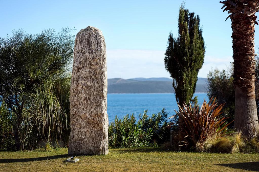 a tallolith in the grass next to trees and water at Silver Bay Club House in Urla