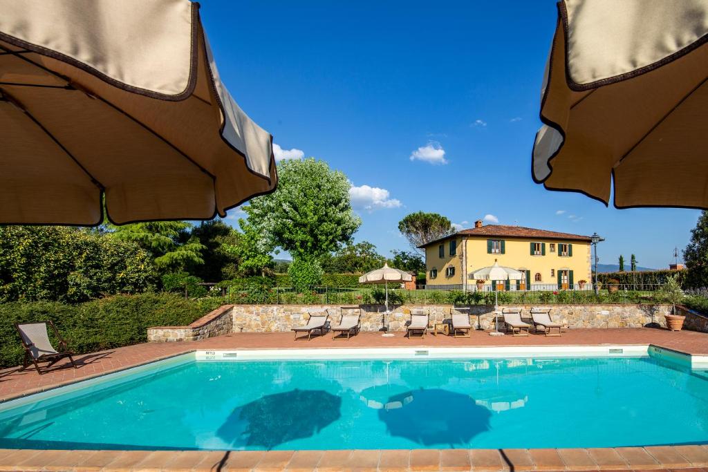 a swimming pool with two umbrellas and a house at Villa Farmi by MMega in Bibbiena