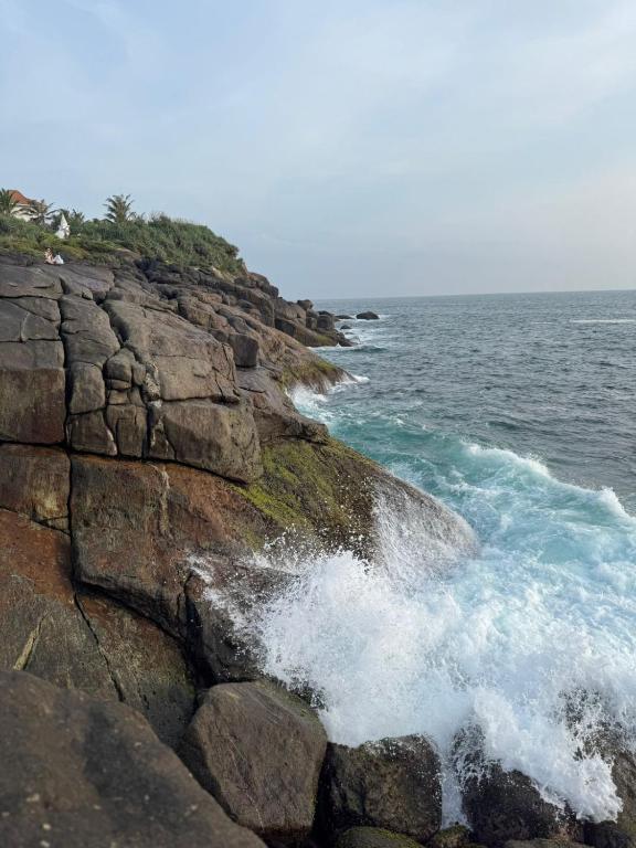 a group of waves crashing on a rocky beach at Rock Hill Hotel in Galle