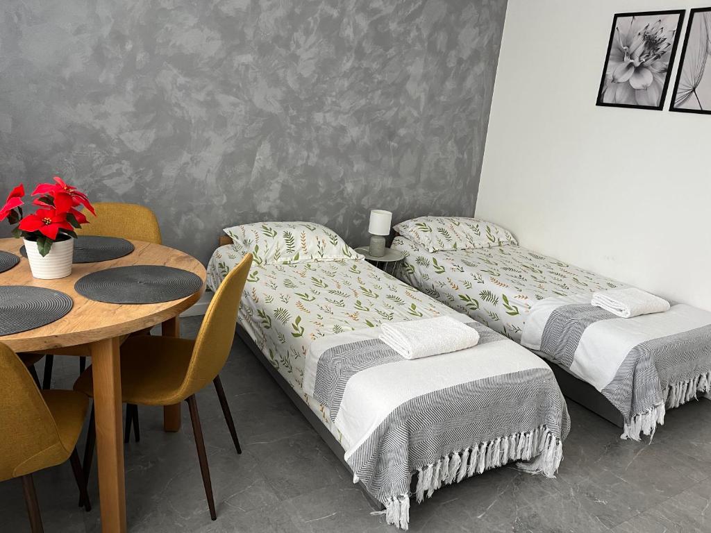 two beds in a room with a table and a table and chairs at Apartament Szpitalna Możliwość wystawiania Faktur, WI-FI in Suwałki