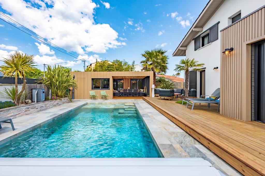 a swimming pool with a deck and a house at La Petite Californie - Piscine in Anglet