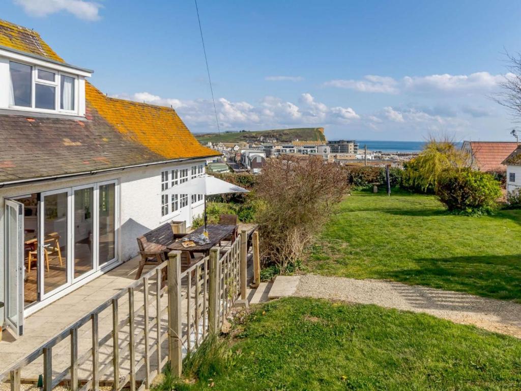 a cottage with a deck and a view of the ocean at 4 Bed in Bridport oc-dc083 in West Bay