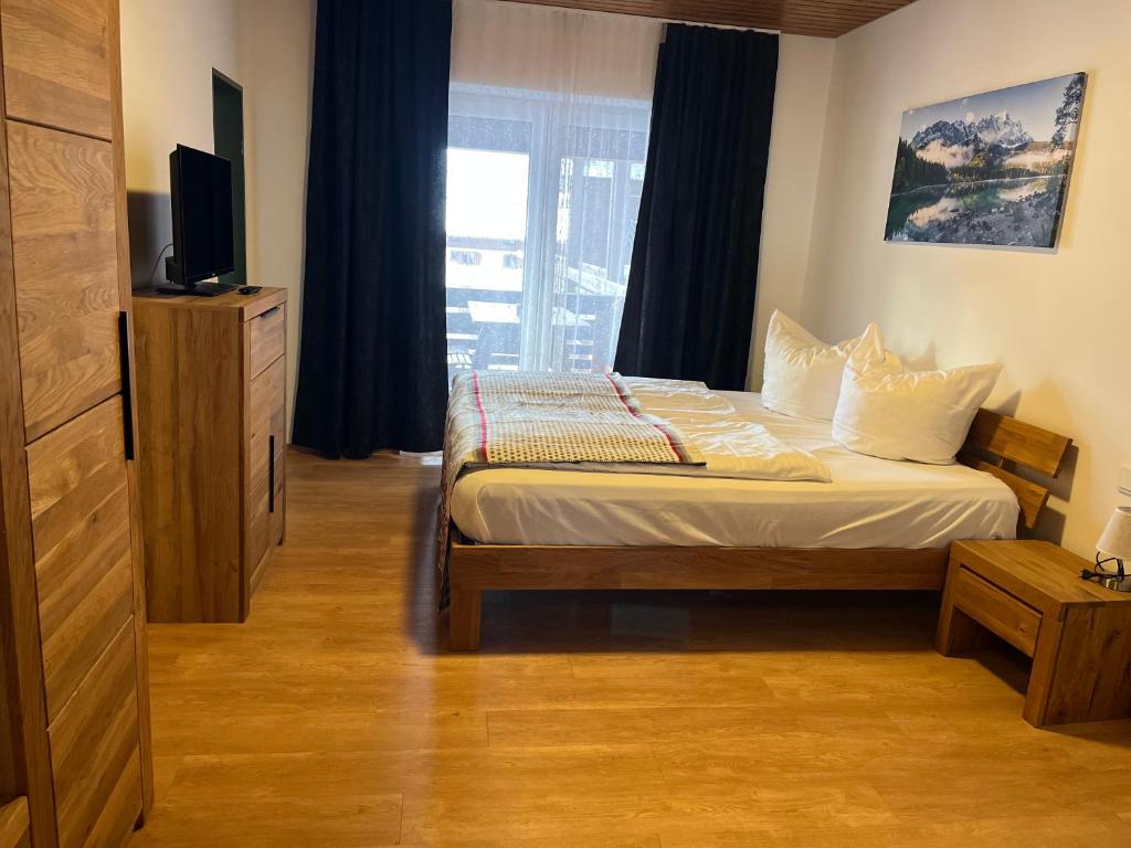 a bedroom with a bed with a television and a window at Ferienwohnung zum Breu im Löwen in Reit im Winkl