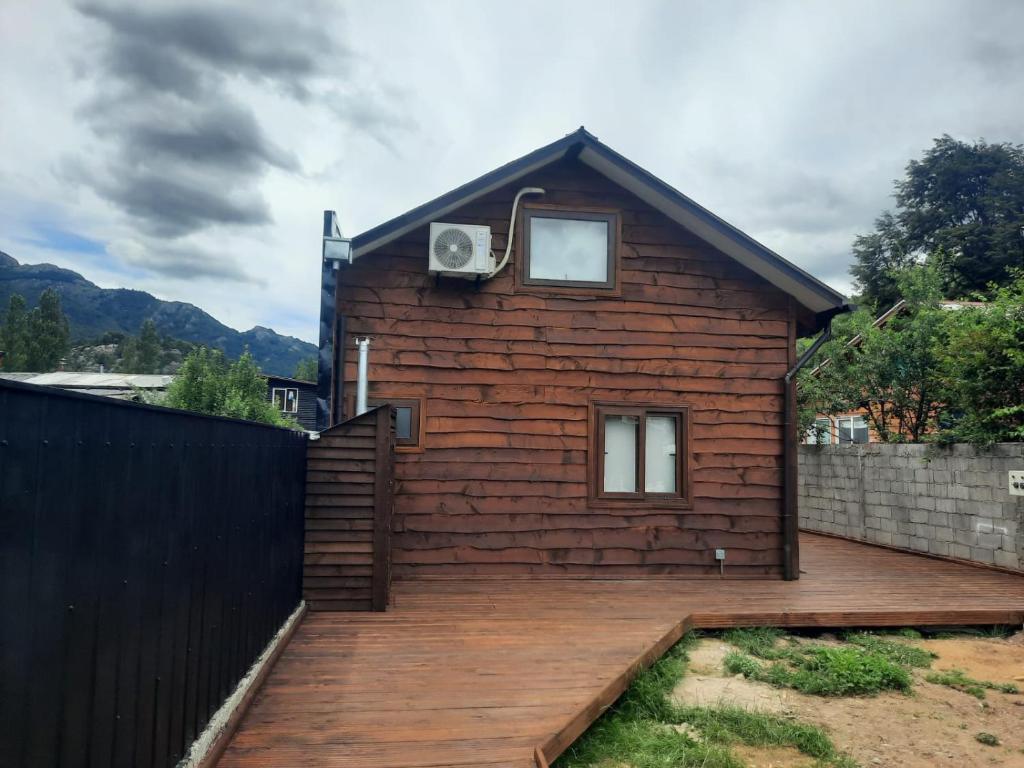 a house with a wooden deck in front of it at Cabañas Entre Cerros y Ríos in Futaleufú