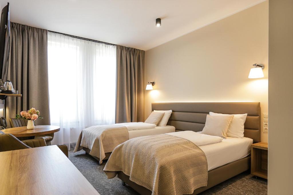 ein Hotelzimmer mit zwei Betten und einem Tisch in der Unterkunft Poznań West Hotel - Airport in Posen