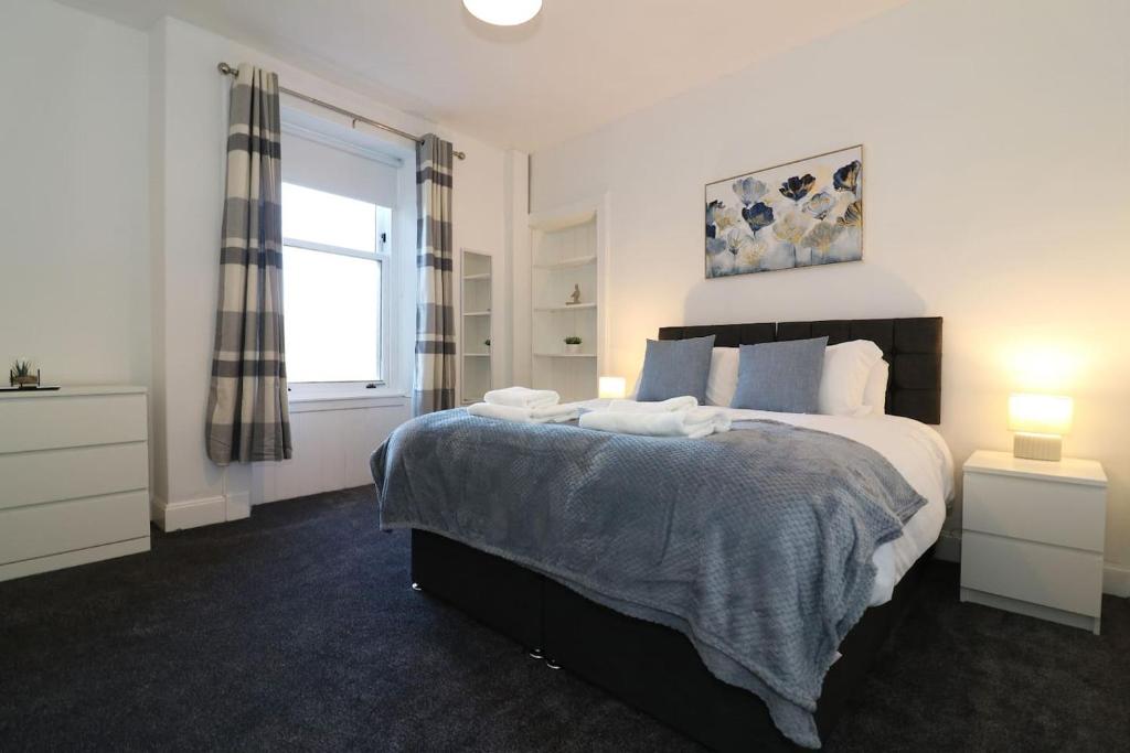 a bedroom with a large bed and a window at Modern 2 Bedroom Cottage Flat in Stenhousemuir
