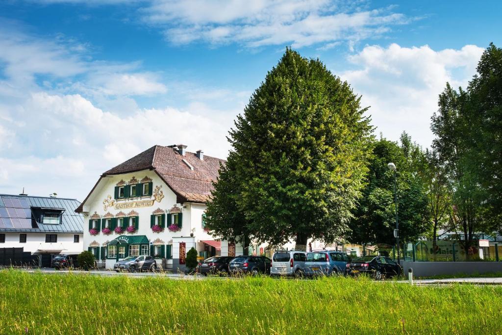 a large white house with cars parked in front of it at Hotel Apartment Das Au- Gut in Hallein