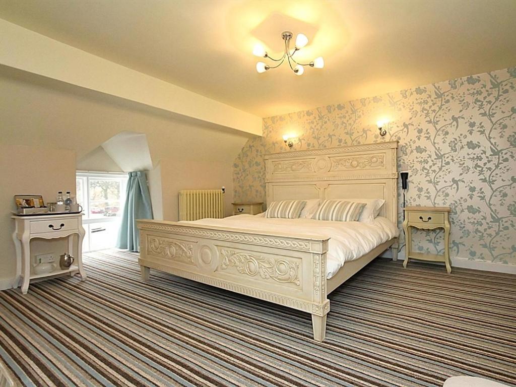 a bedroom with a large white bed and floral wallpaper at The Hand at Llanarmon in Llanarmon Dyffryn-Ceiriog