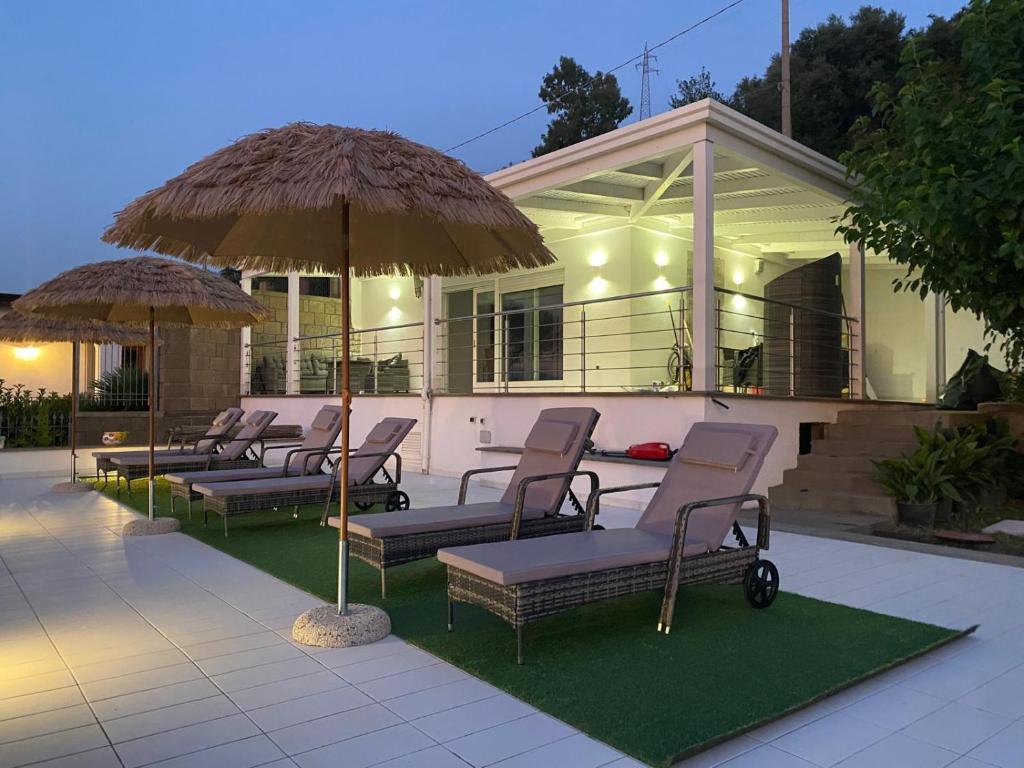 a group of chairs and umbrellas in front of a house at Villa Ice Sorrento in Sorrento
