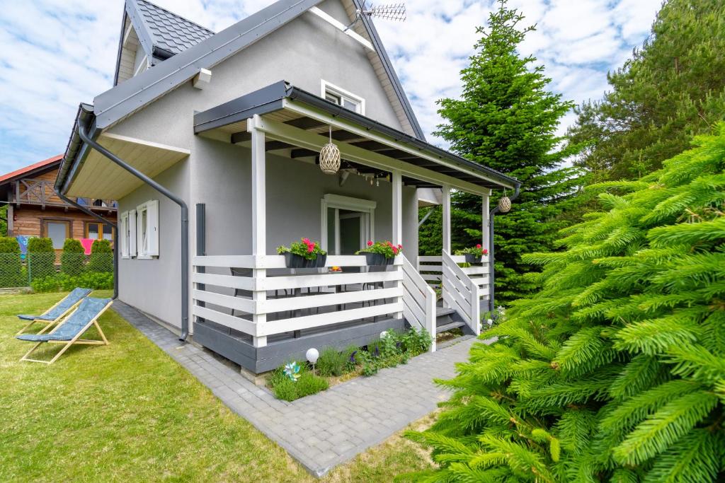 a small house with a porch with flowers in a yard at Hacienda-Dębina in Debina