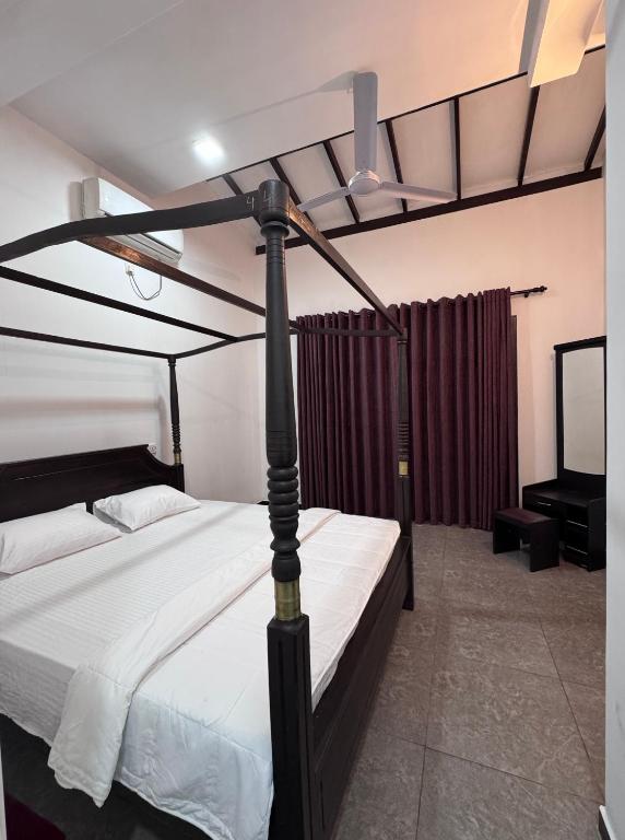 a bedroom with a black and white bed and a tv at Una Stay in Unawatuna