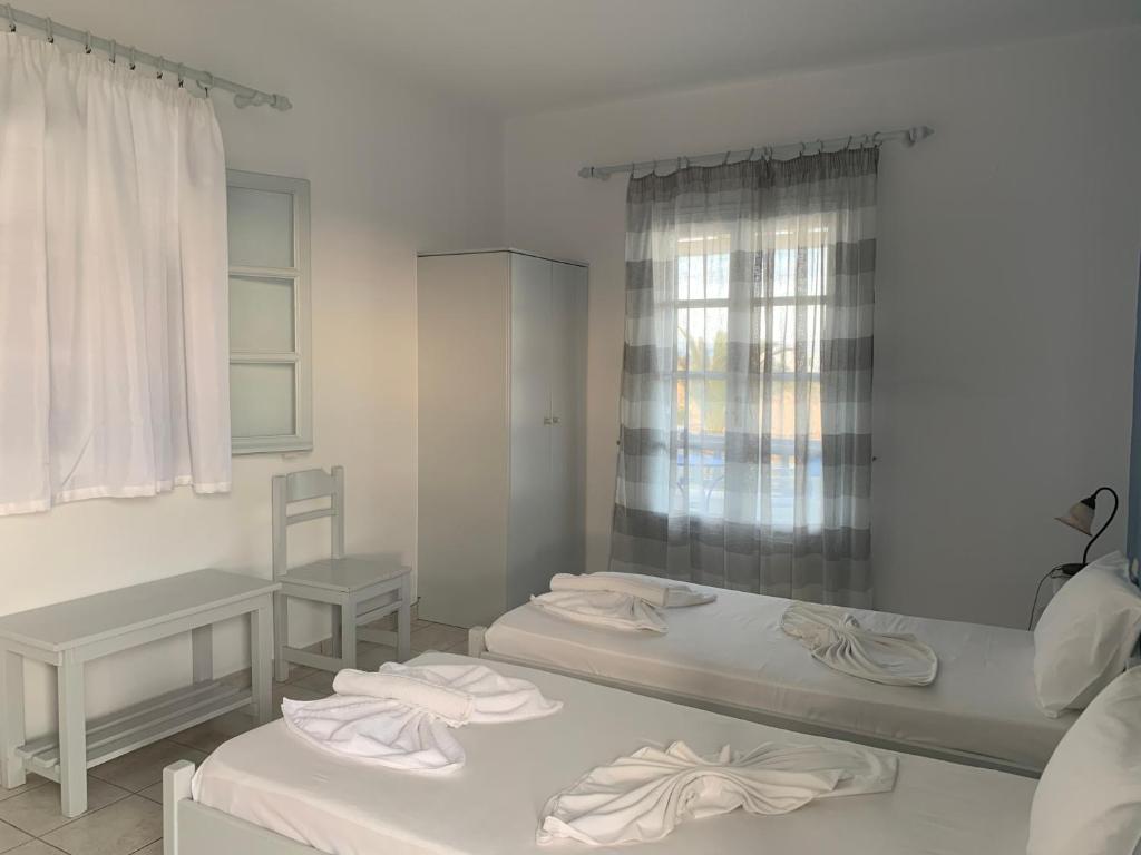 a room with two beds and a table and a window at Melissa Rooms in Koufonisia