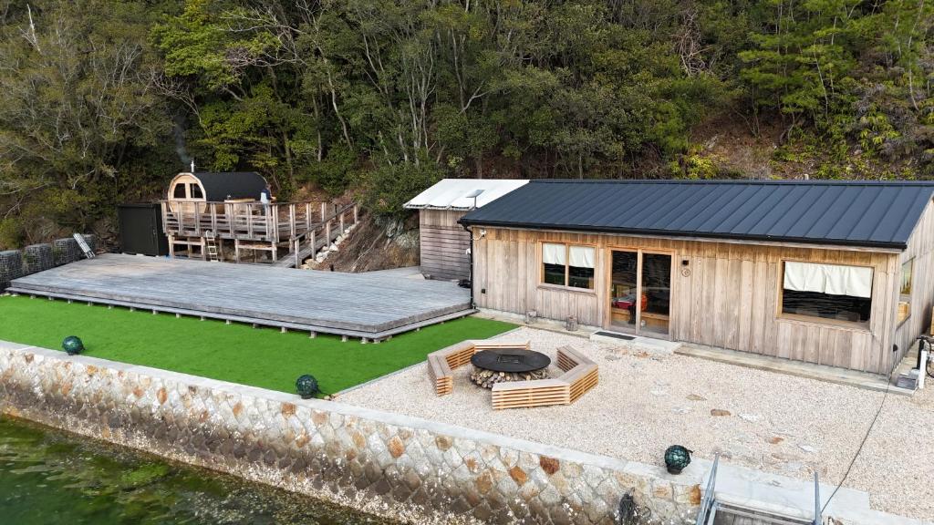 ein kleines Haus mit Terrasse direkt an einem Gewässer in der Unterkunft UMILABO Retreat - 船で行く海辺のプライベート宿泊 in Shima