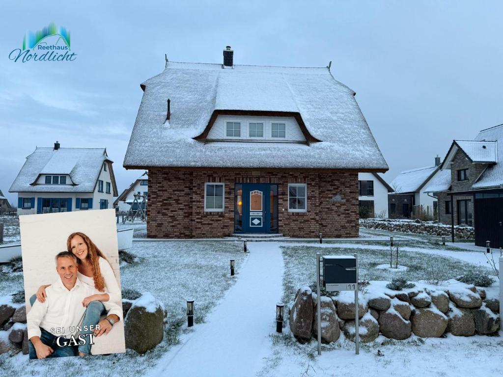 a picture of a couple in front of a house in the snow at Reethaus Nordlicht A Top-class in Dranske