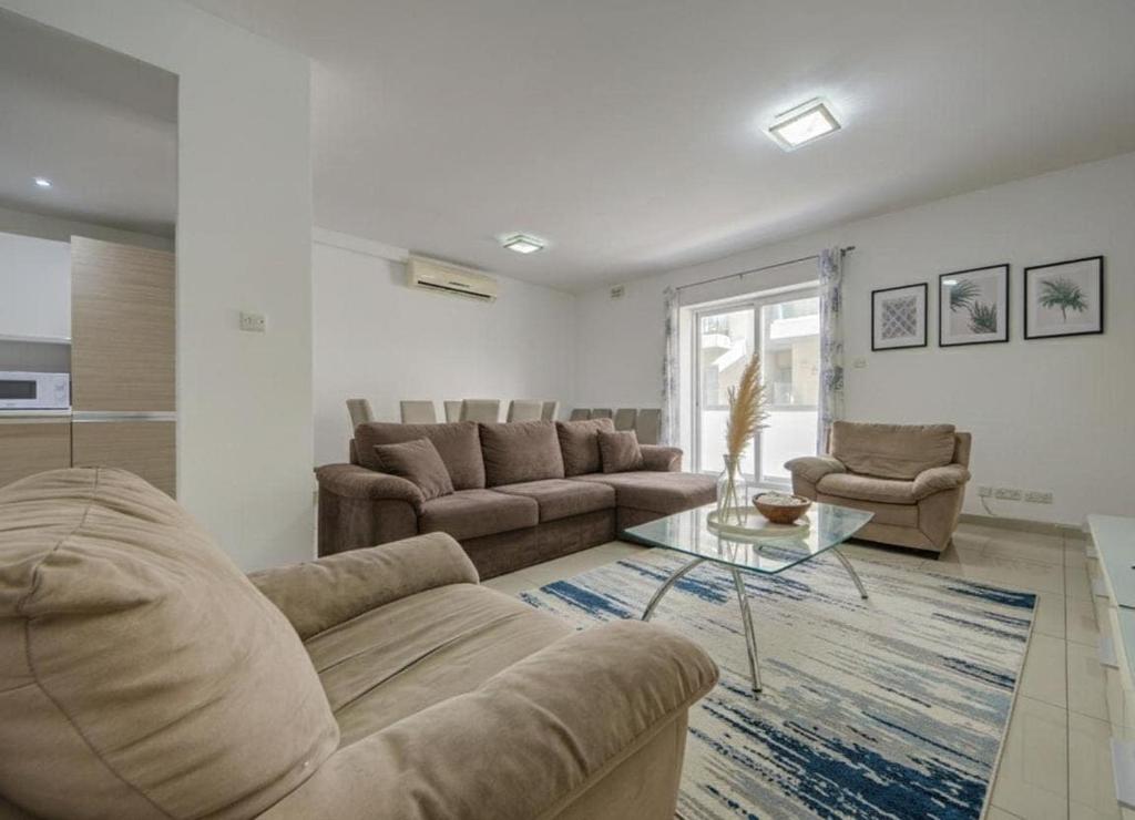 a living room with two couches and a table at Central, spacious apartment with Sea Views in St. Paul's Bay