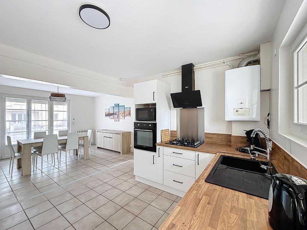 a kitchen with white cabinets and a table with chairs at Cozy Alclau in Mimizan