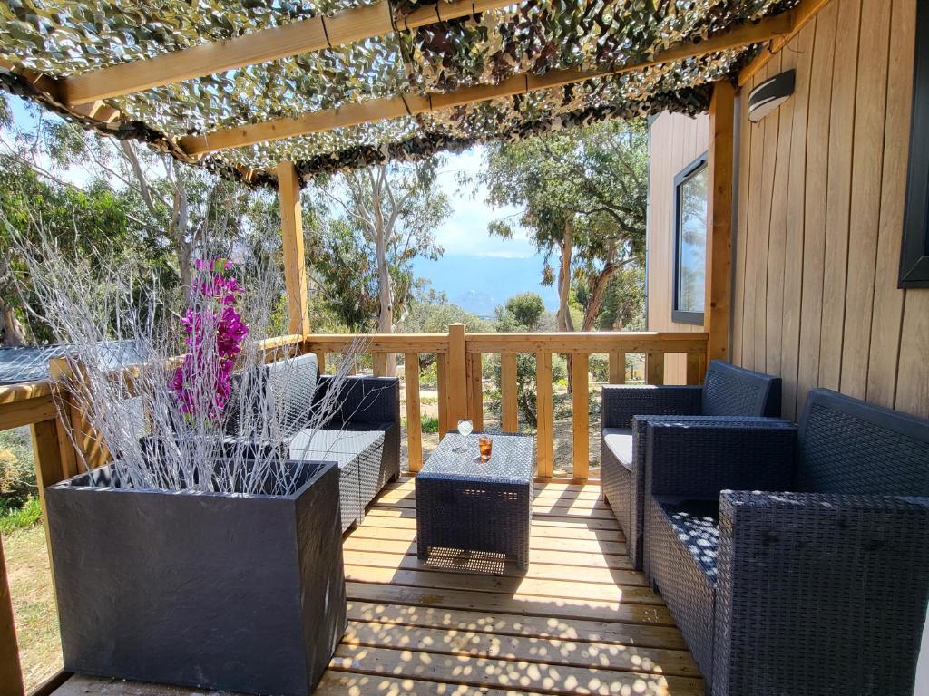 a patio with chairs and a pergola and a table at Bungalow le Sartène in Lumio