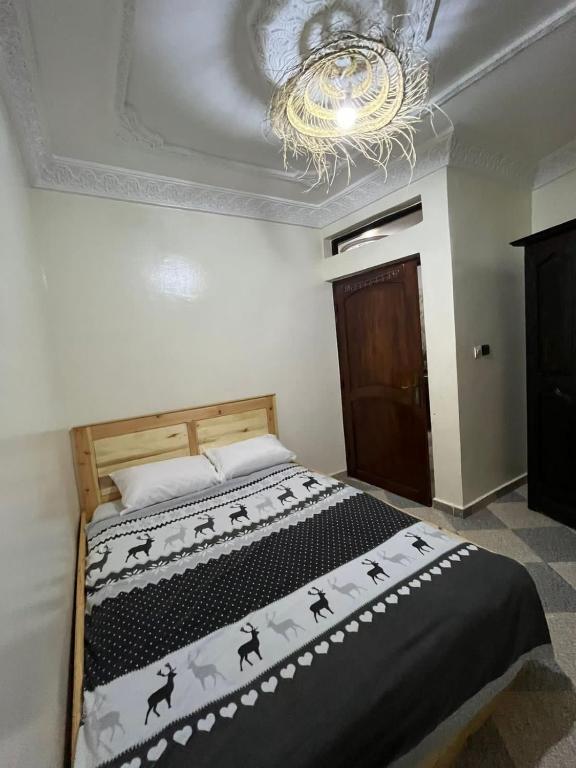 a bedroom with a bed with a chandelier at Yousef appartement in Taghazout