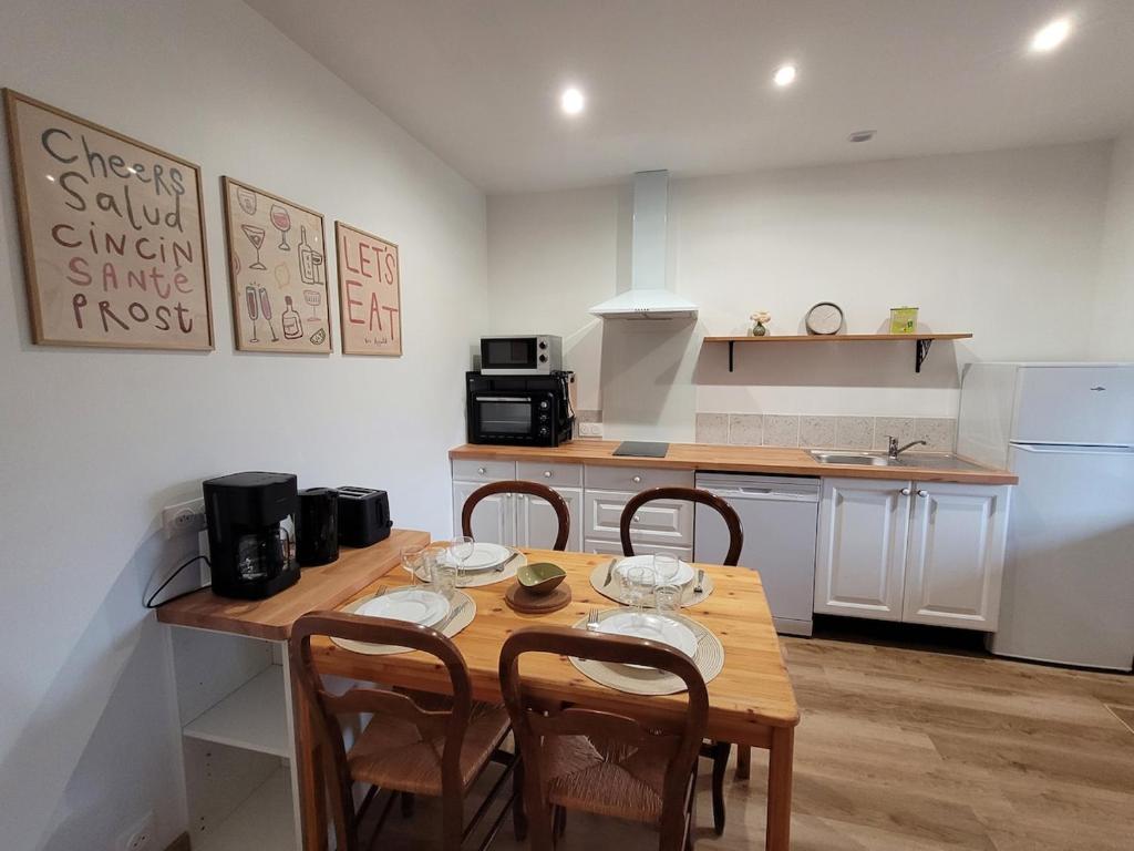 a kitchen with a wooden table and chairs in it at Gîte L'alcôve in Issendolus