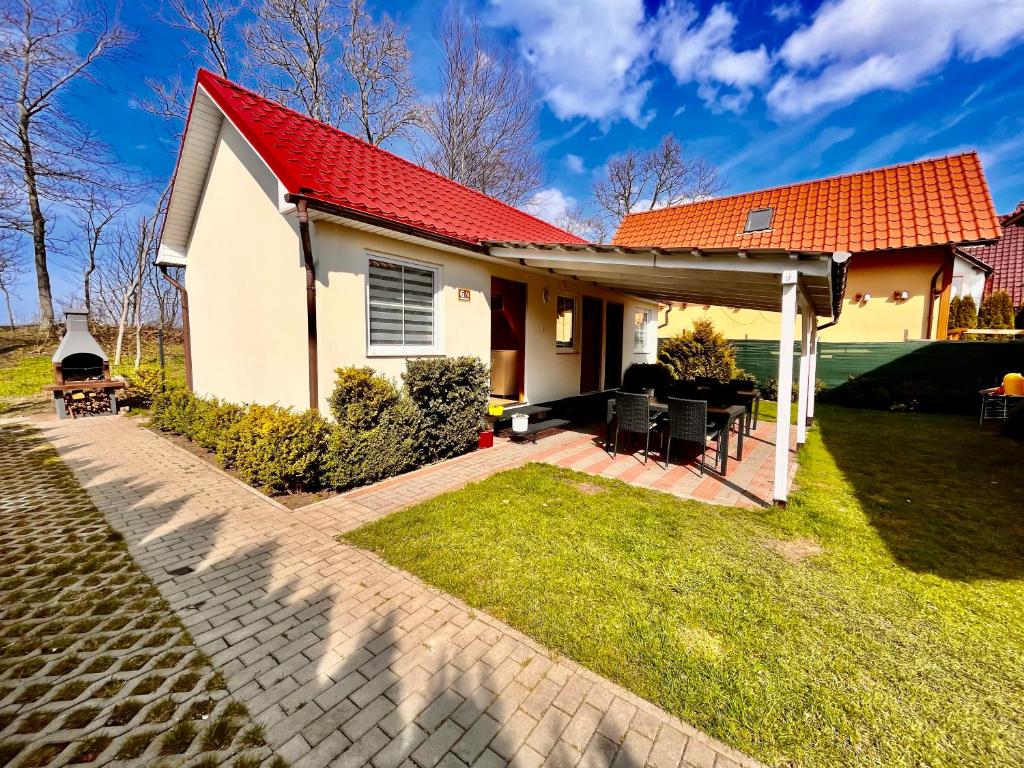 a house with a red roof and a patio at Pokoje Nad Klifem in Trzęsacz