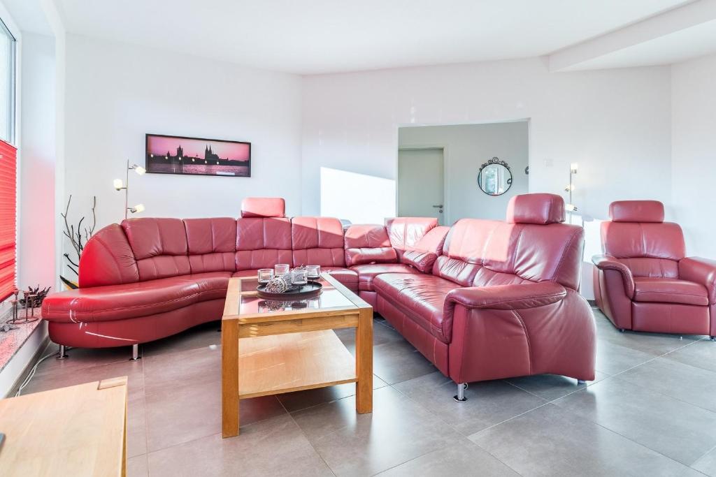 a red leather couch and chairs in a living room at Ferienwohnung "Colonia" in Klütz