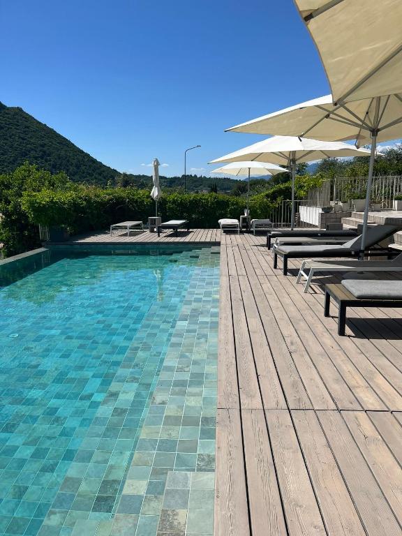a swimming pool with benches and umbrellas on a deck at Biancaleo Homes in Affi