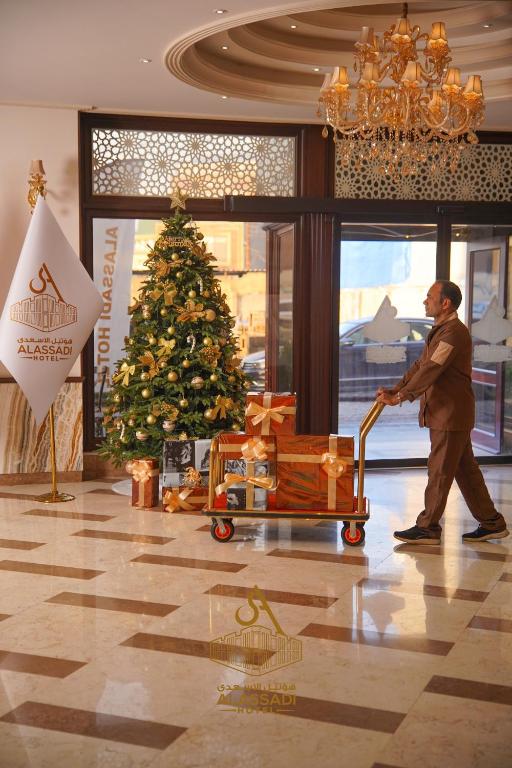 a man pushing a shopping cart in front of a christmas tree at Al-Assadi Hotel in Erbil