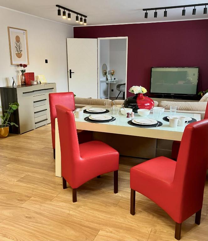 a living room with a table and red chairs at Bytom Syrah in Bytom