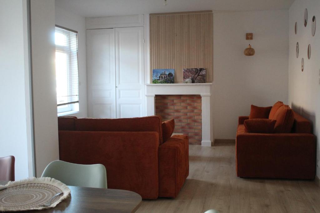 a living room with two couches and a fireplace at Le nid des Huttes in Gravelines