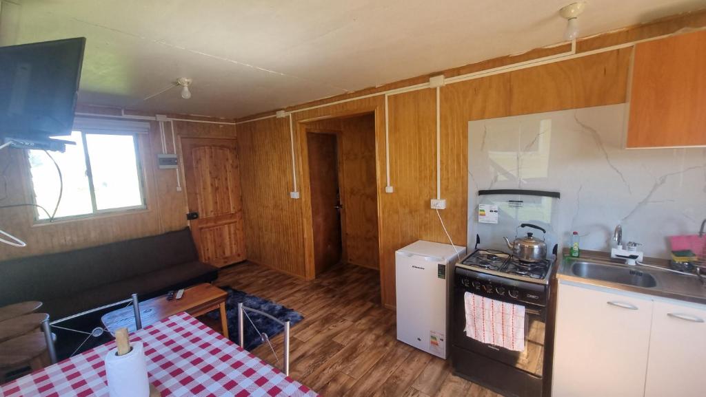 a kitchen with a stove and a sink and a table at cabañas cubero in Gualaihue