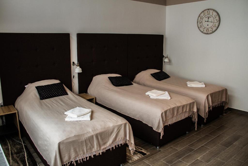 dwa łóżka w pokoju z zegarem na ścianie w obiekcie Rooms Rebolj w mieście Osijek