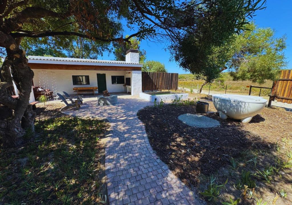 a garden with a large stone tub in front of a house at Fisherman's Cottages at Blombosch Game Farm in Yzerfontein