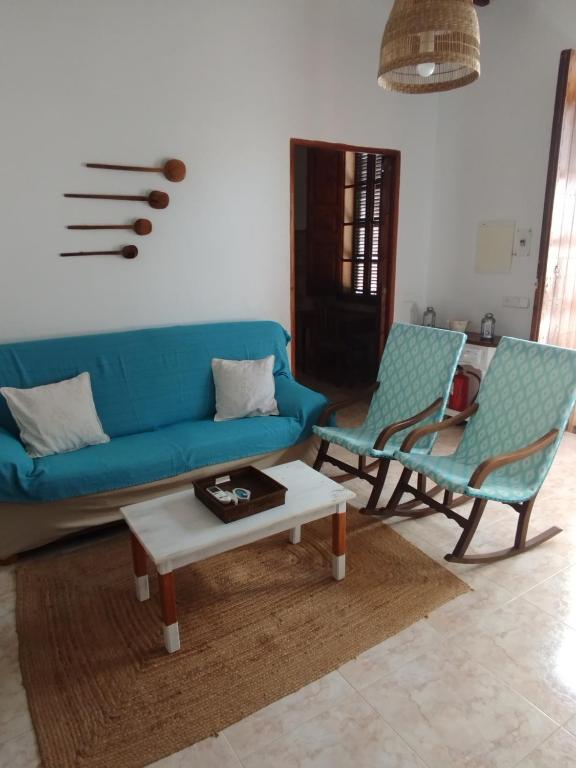 a living room with a blue couch and two chairs at ca sa tia in Santanyi
