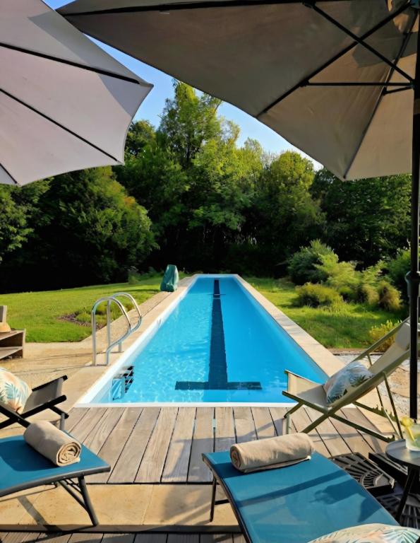 a swimming pool with two chairs and an umbrella at La Maison aux pieds des Pyrénées - Piscine d'exception de 25m in Espoey