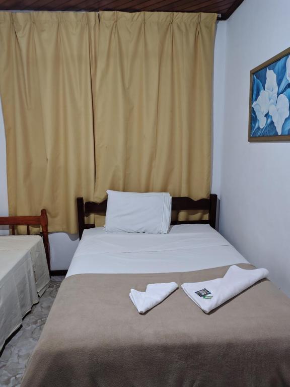 a bedroom with two beds with towels on them at Hostel Palhoça in Palhoça
