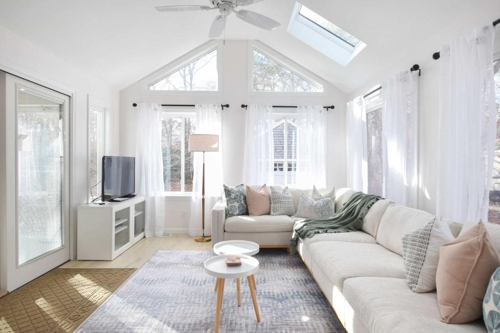 a white living room with a couch and a tv at Spacious Home by Beach Dog Welcome in Brewster