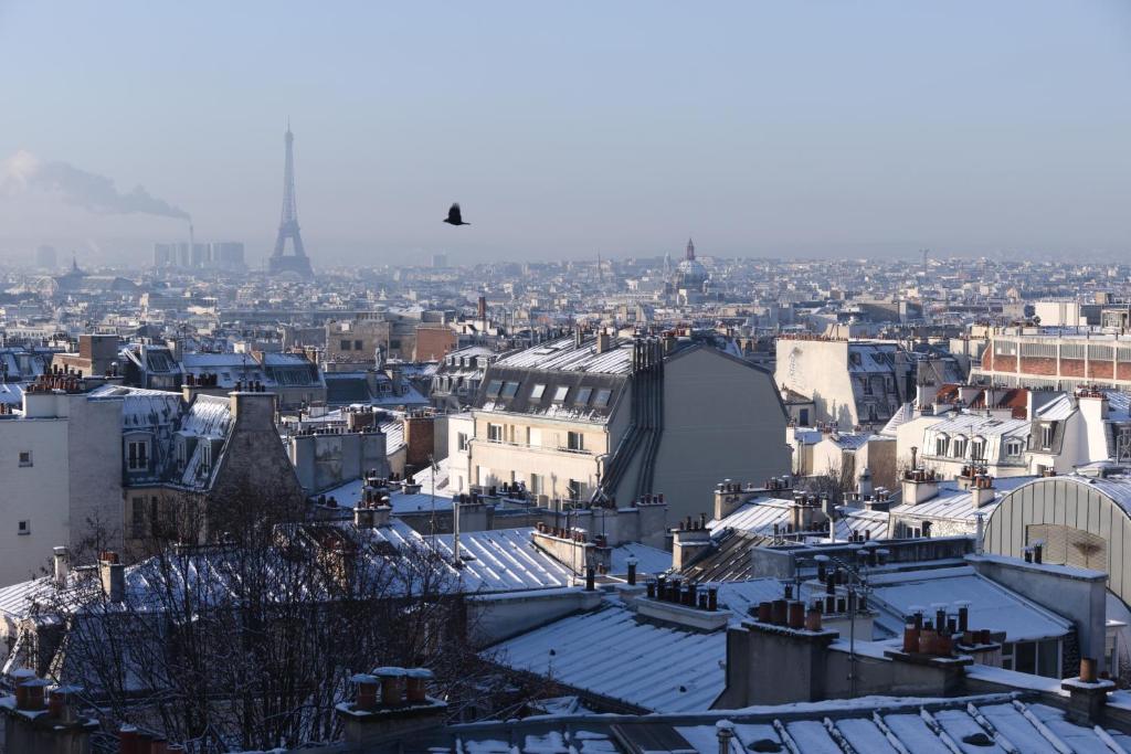 a view of a city in the snow with the eiffel tower at Hôtel Regyn's Montmartre in Paris
