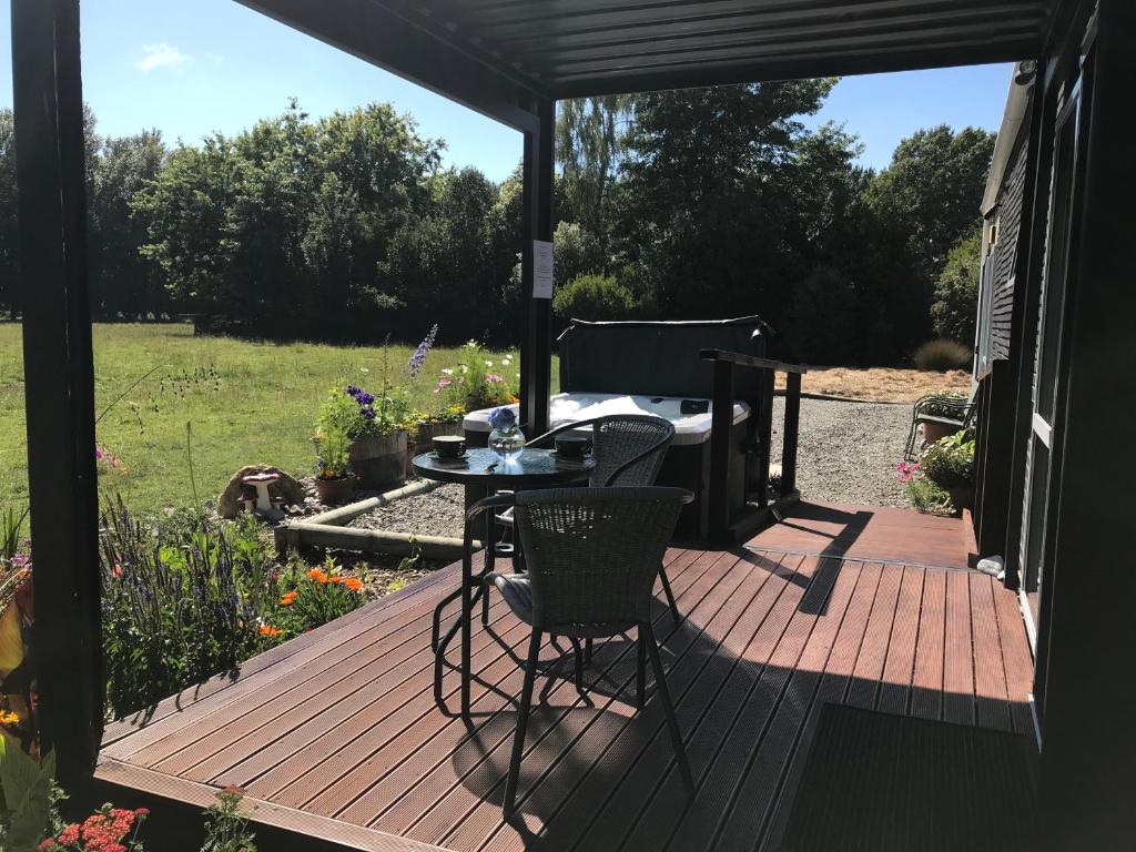 a wooden deck with a table and chairs on it at Brookside Country Escape 40 minutes to CHC Airport in Leeston