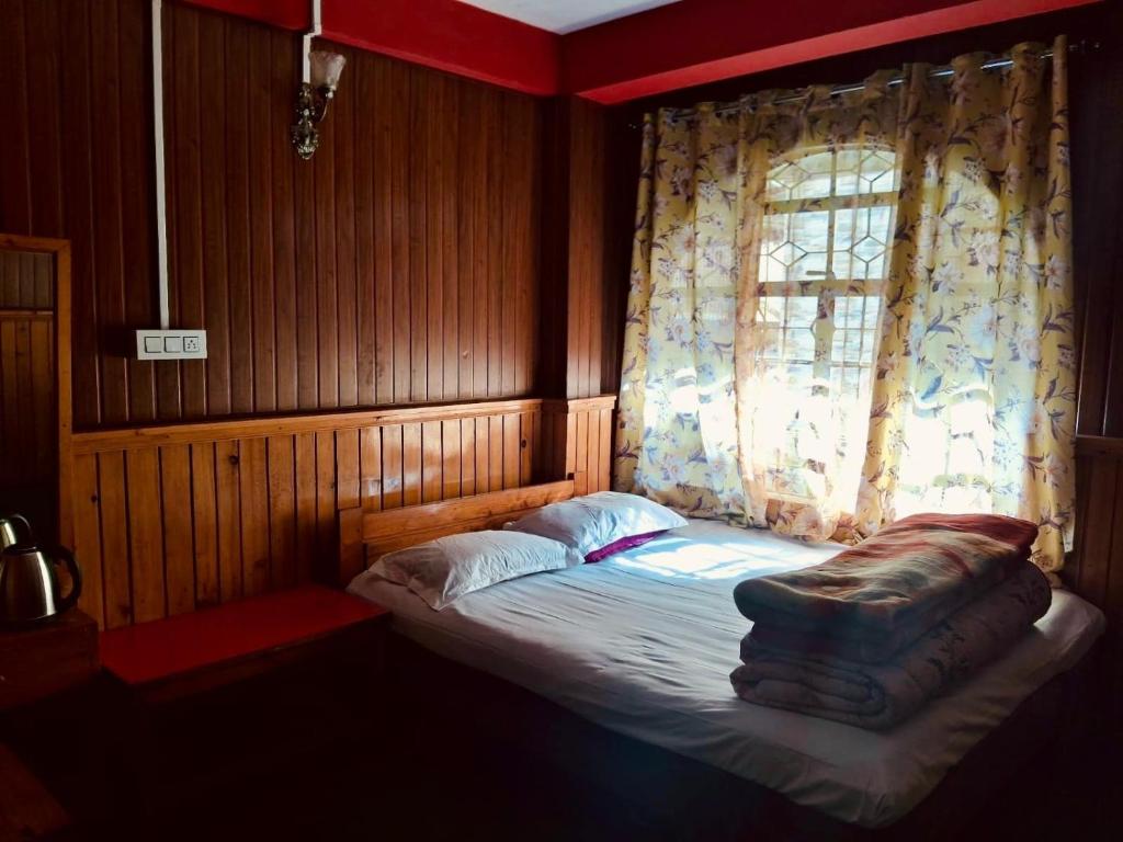 a small bed in a room with a window at Tenzing Homestay in Kalimpong