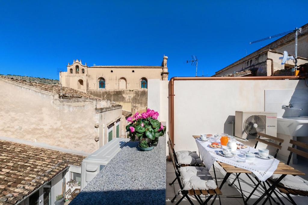 a balcony with a table and flowers on a building at Busacca Suite in Scicli