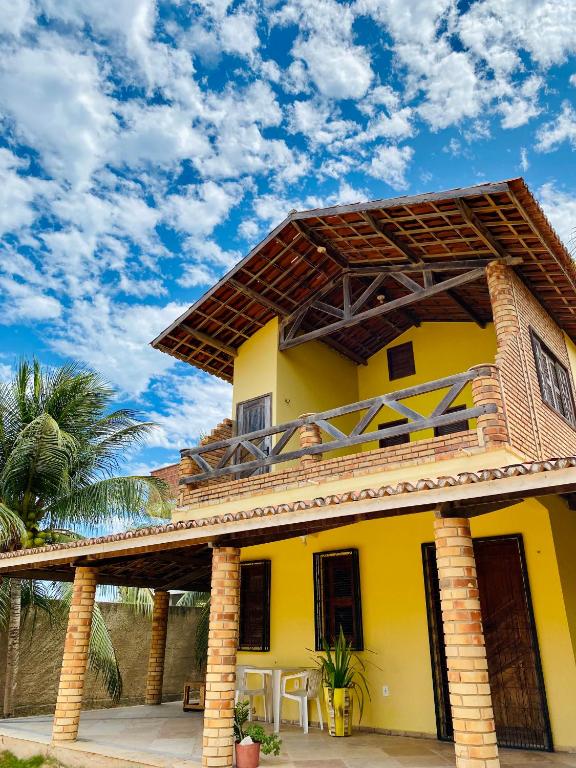 a yellow house with a balcony on top of it at Casa Caju in Aracati