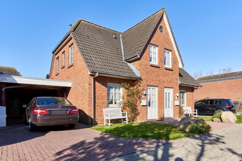 a brick house with a car parked in the driveway at Muschelsucher 2 in Nordstrand