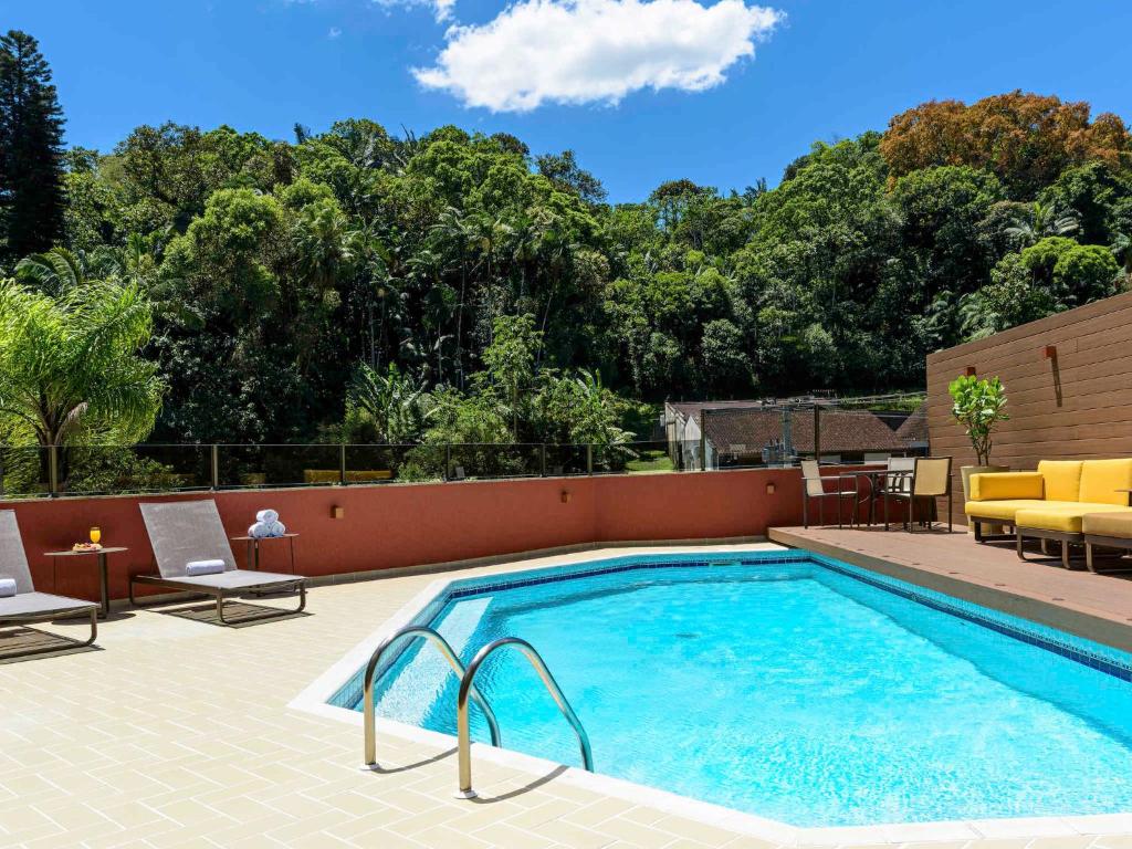 a swimming pool on a patio with chairs and a table at Prinz Loft in Joinville