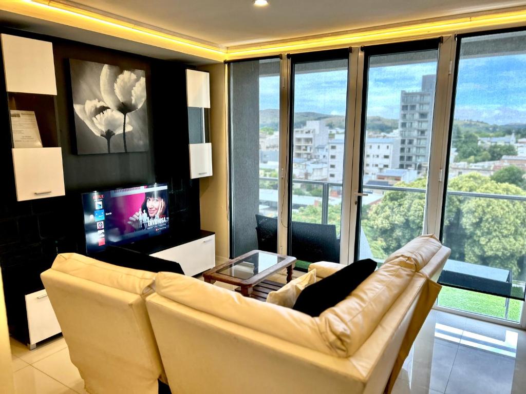 a living room with a couch and a tv at Residencias Tandil Centro con vistas - Pinto in Tandil