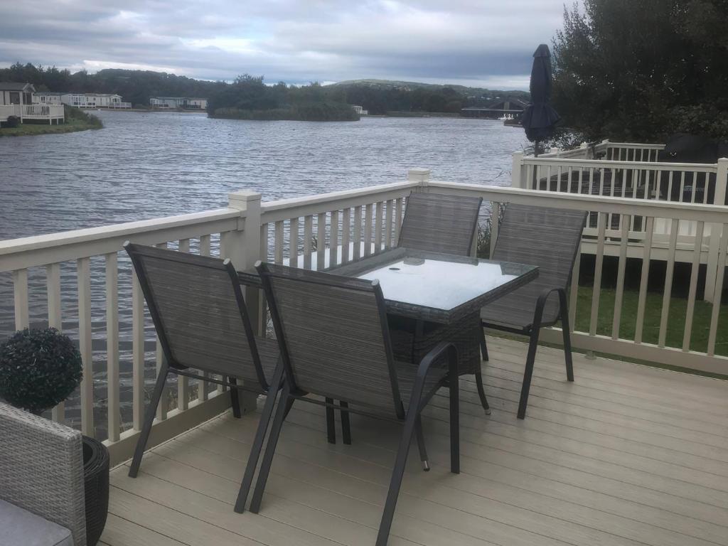 Ein Tisch und Stühle auf einer Terrasse neben dem Wasser in der Unterkunft Annalake in Grange Over Sands