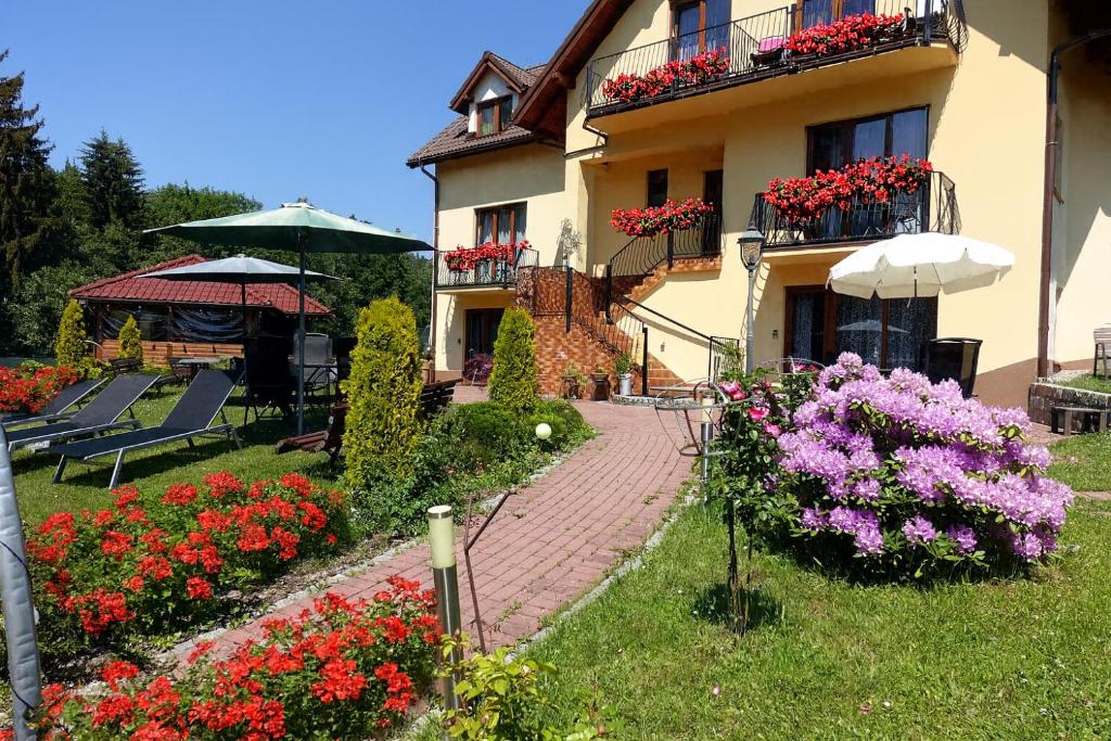 a house with flowers in front of it and an umbrella at Apartamenty u Ani in Kudowa-Zdrój