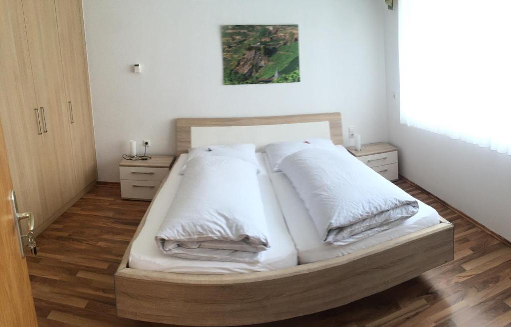 a bed with white sheets and pillows in a room at Gästehaus Alfons und Marianne Eifel in Trittenheim