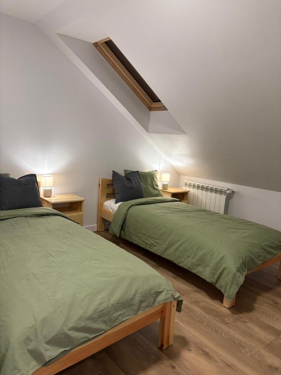 a bedroom with two beds with green sheets and lamps at Borówkowy domek in Janik