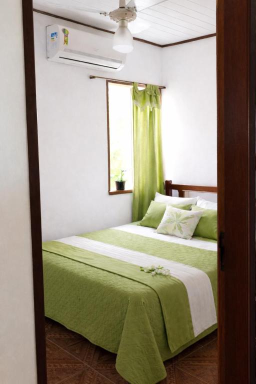 a bedroom with two beds with green sheets and a window at Kalena Suítes in Lençóis