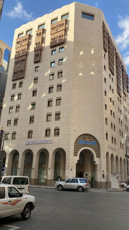 a large building with cars parked in front of it at Hayah Grand Hotel Ex Al Jaad Madinah Hotel in Medina